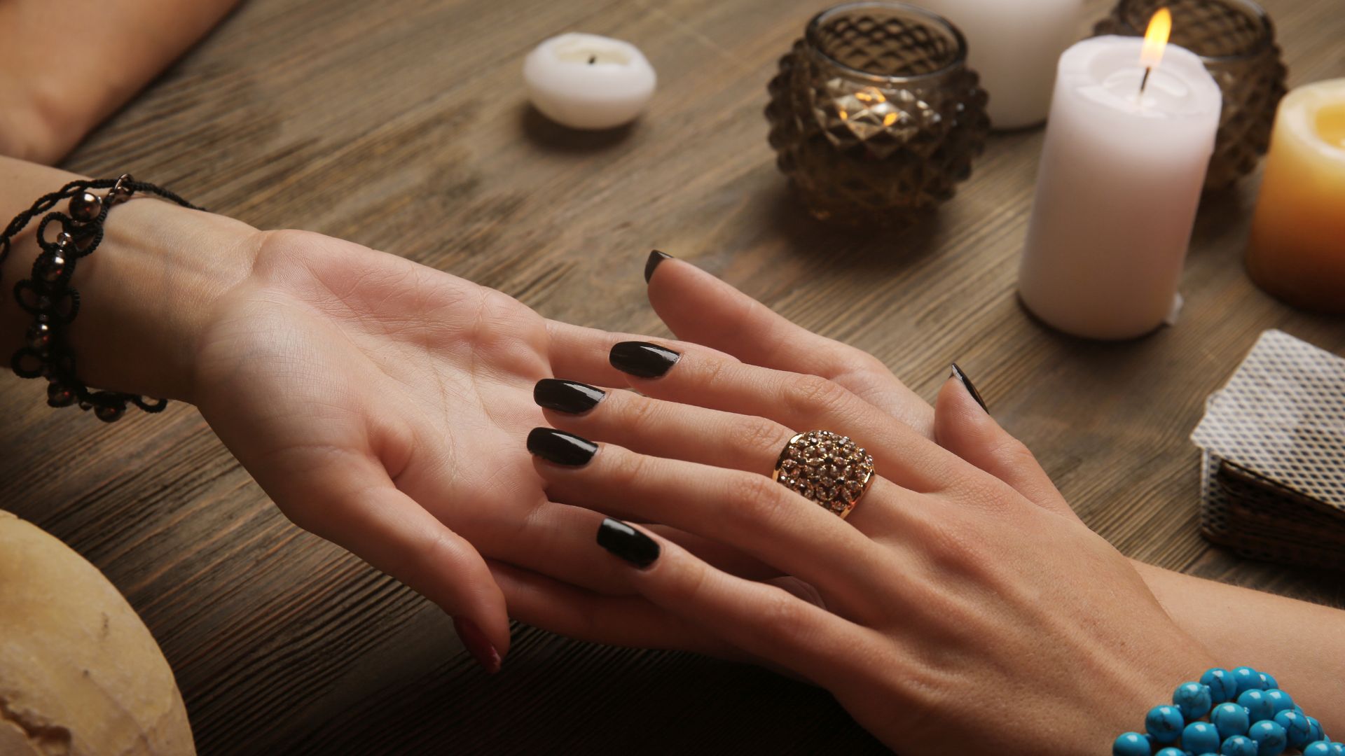 A woman's hands with black nail polish and a ring