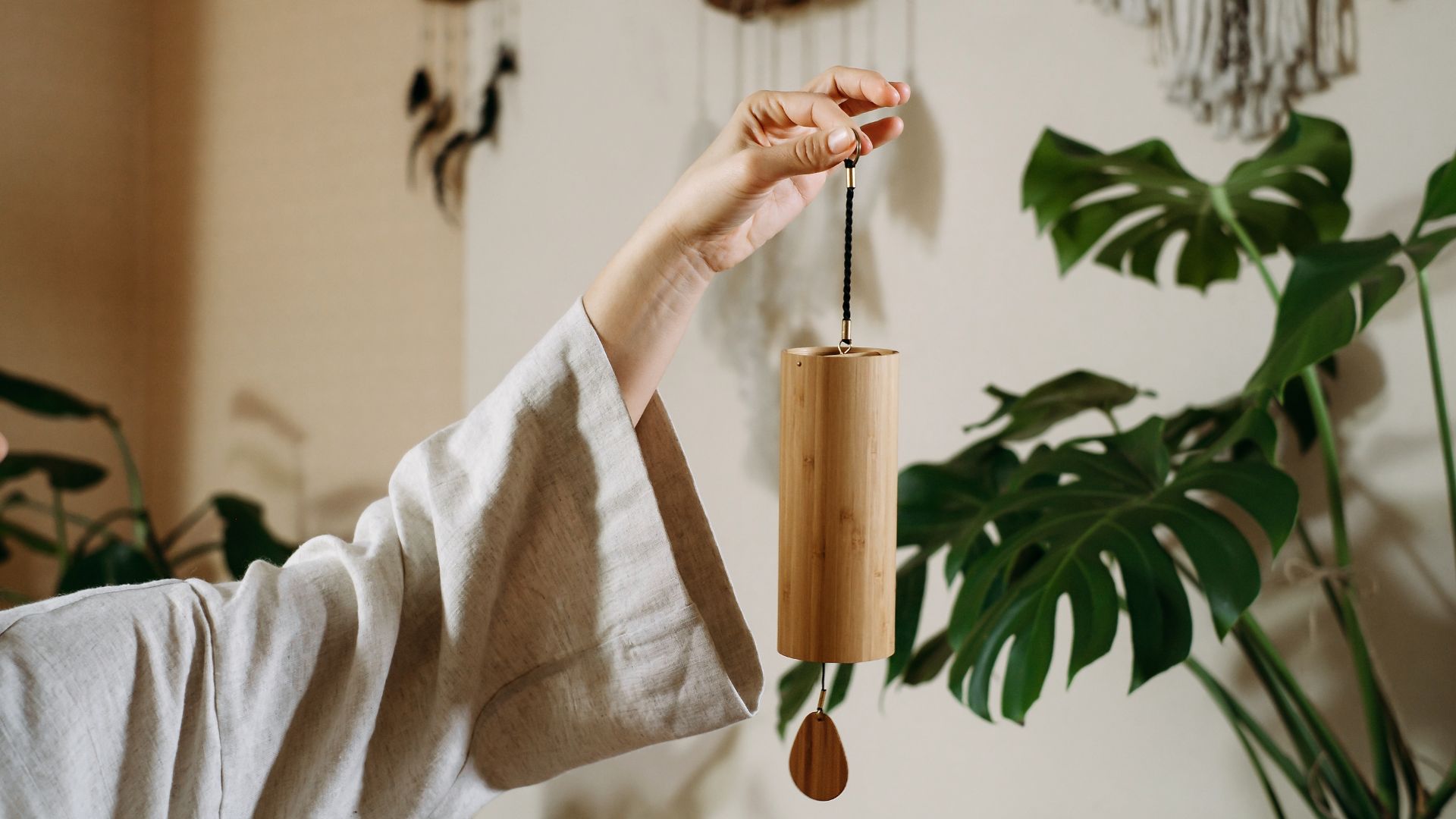 A woman holding a wooden wind chime in her hand