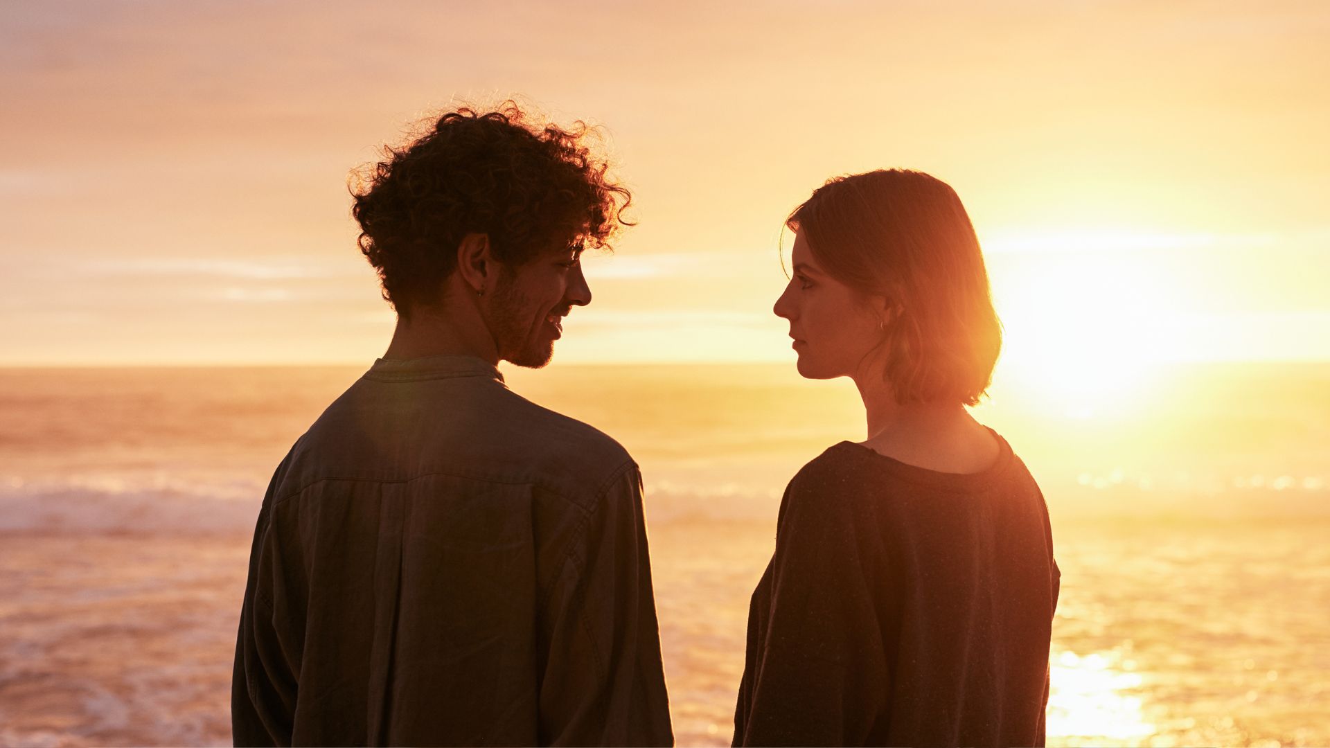 A couple of people standing next to each other near the ocean