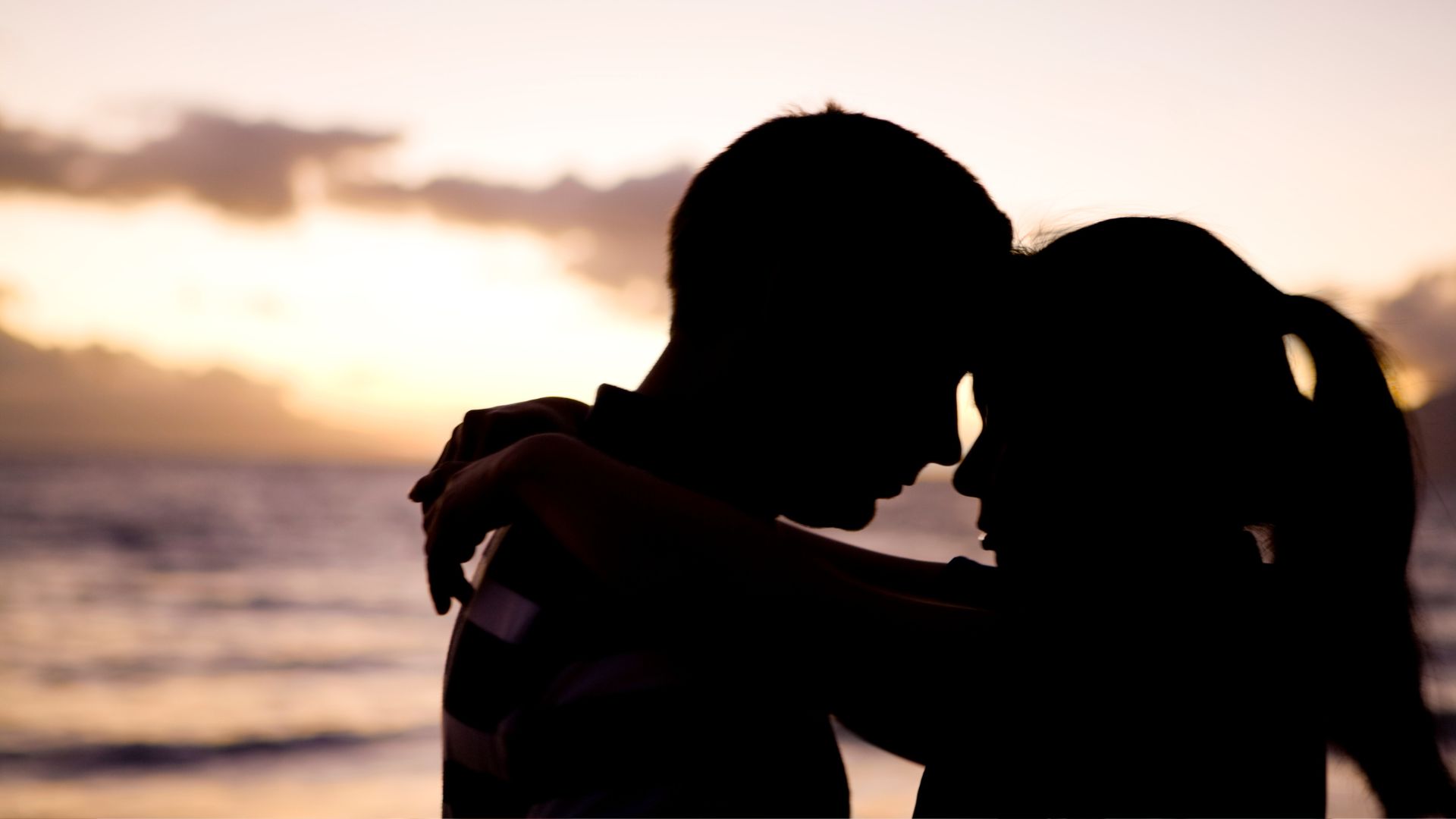 A man and a woman standing next to each other in front of the ocean